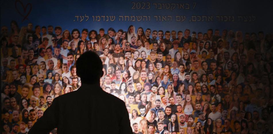 Una persona ve un collage de familiares, asisten al monumento a Nova cerca del Kibbutz Reim en el sur de Israel, durante el primer aniversario. de los ataques del 7 de octubre de 2024. (Foto de John Wessels