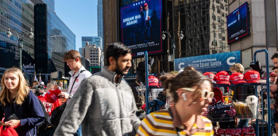 Un vendedor vende mercadería mientras los partidarios del candidato presidencial republicano, el expresidente de los Estados Unidos Donald Trump, se reúnen afuera del Madison Square Garden antes de un mitin de campaña el 27 de octubre de 2024 en la ciudad de Nueva York. La aparición de Trump en la ciudad tradicionalmente demócrata se produce menos de dos semanas antes de las elecciones presidenciales. La vicepresidenta Kamala Harris y Trump están empatados en la mayoría de las encuestas nacionales.