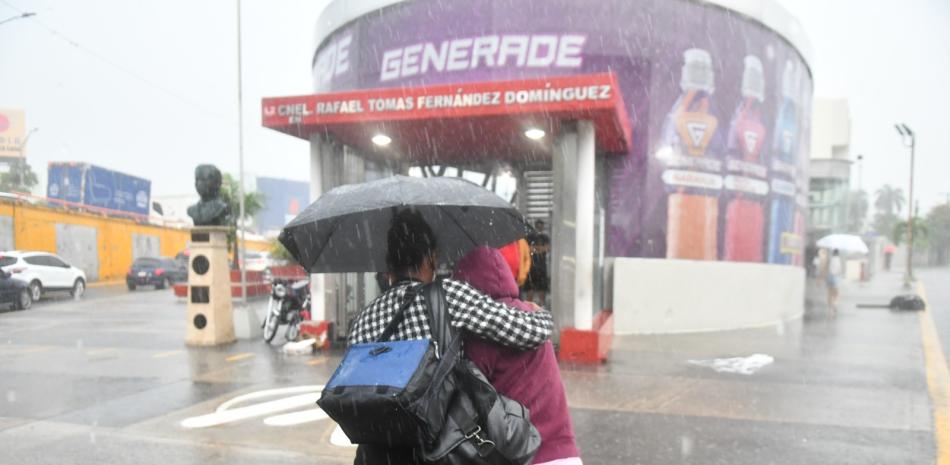 Dos mujeres se cubren de la lluvia mientras caminan a una estación del Metro de Santo Domingo.