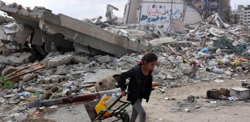 Una niña palestina transporta agua mientras pasa junto a un edificio derrumbado en la ciudad de Gaza el 2 de noviembre de 2024, en medio de la guerra entre Israel y Hamás