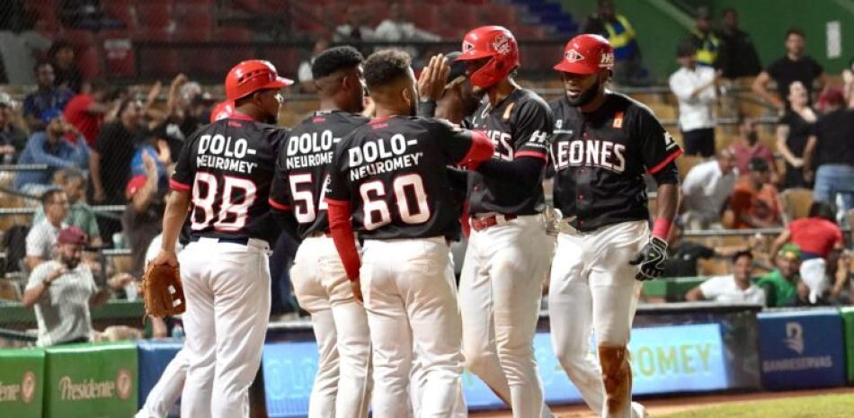 Jugadores de los Leones celebran luego de llegar al plato.