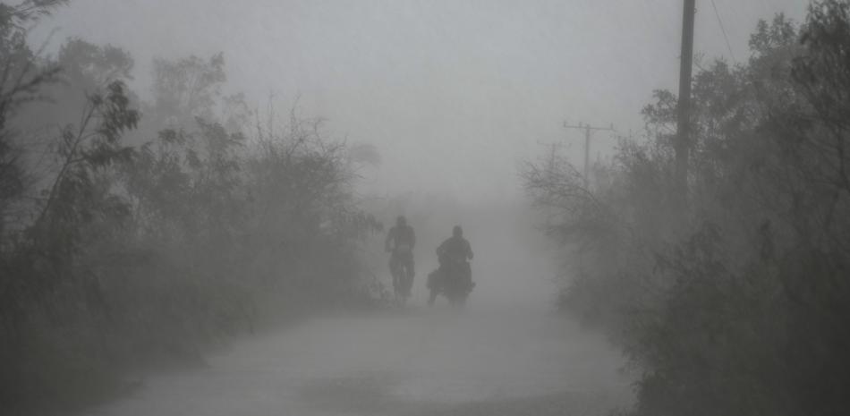 La gente viaja bajo la lluvia tras el paso del huracán Rafael en Guanimar, Cuba, el jueves 7 de noviembre de 2024