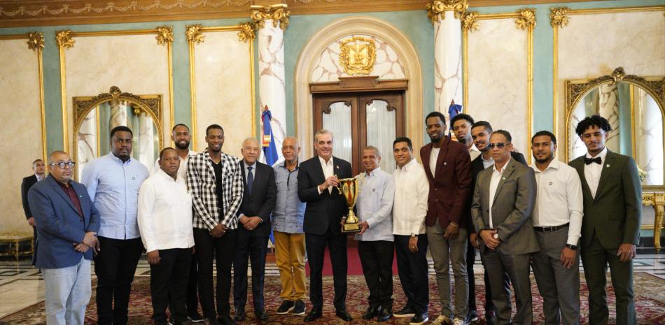 El presidente Luis Abinader y Leo Corproán, asesor del club Mauricio Báez, sostienen el trofeo de campeón junto a los jugadores, el dirigente Melvyn Nadal, así como José --Boyón-- Domínguez y Américo Celado, titulares de esa institución clubística y de la ACD, respectivamente.