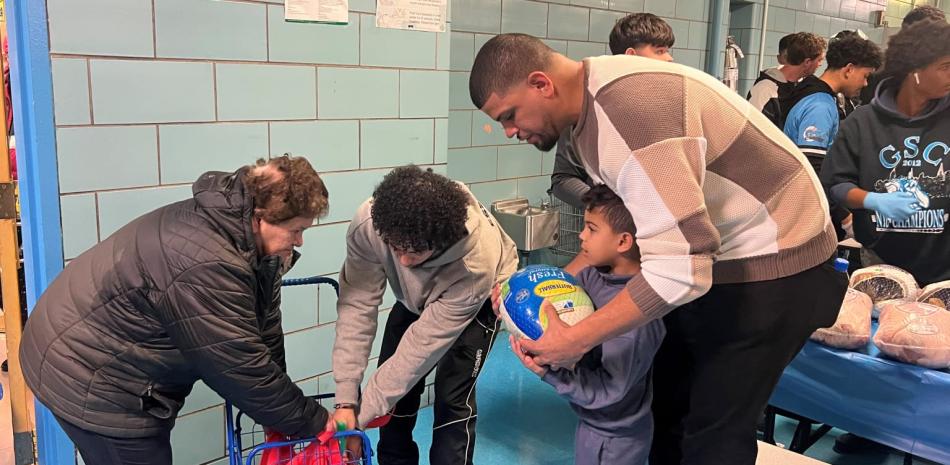 El expitcher Dellin betances mientras repartía fundas de pavos a niños en una escuela de Brooklyn.