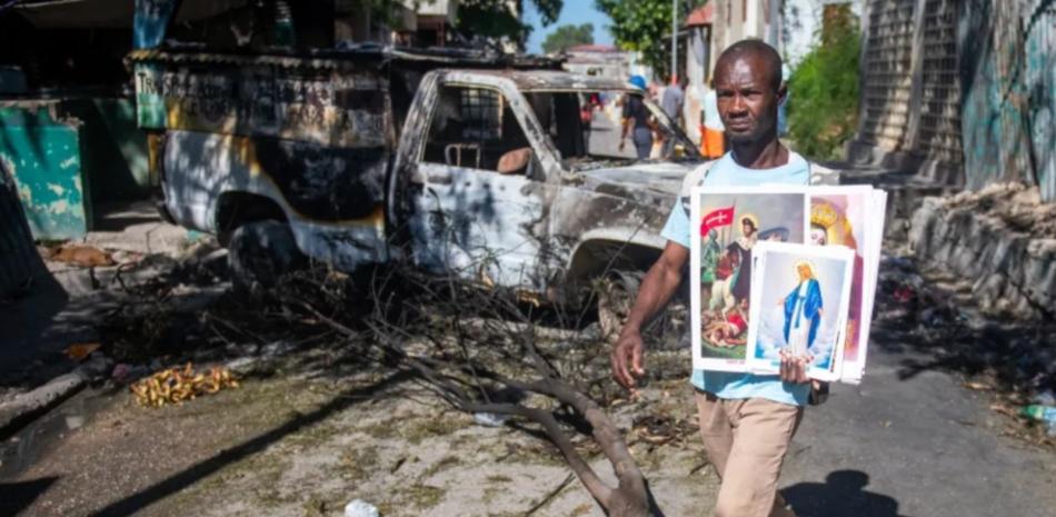 Un hombre sostiene imágenes religiosas en una calle de Poste Marchand, en Puerto Príncipe.