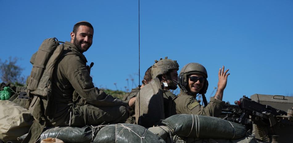 Soldados israelíes saludan a cámara desde un vehículo de transporte blindado mientras cruzan desde la Franja de Gaza a Israel el sábado 18 de enero de 2025.