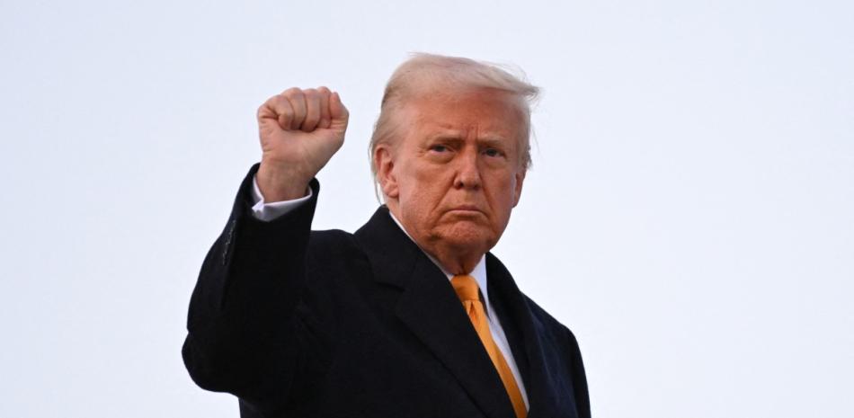 El presidente estadounidense Donald Trump levanta el puño mientras sube al Air Force One en la Base Conjunta Andrews en Maryland el 7 de marzo de 2025