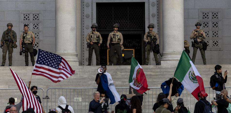 Agentes del sheriff montan guardia mientras los manifestantes se reúnen en las escaleras del Ayuntamiento, mientras continúan las protestas en respuesta a las operaciones federales de inmigración en Los Ángeles el 13 de junio de 2025.