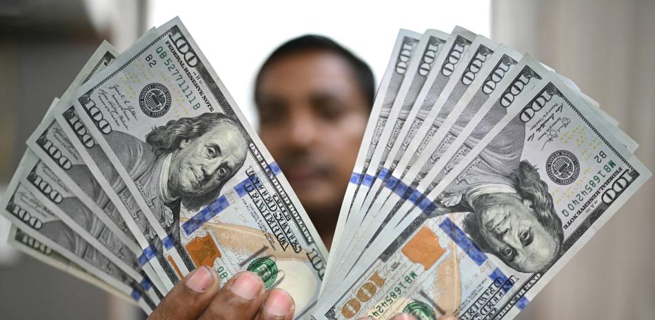 Un trabajador exhibe billetes de dólares estadounidenses en una casa de cambio en Nueva Delhi el 31 de julio de 2025.