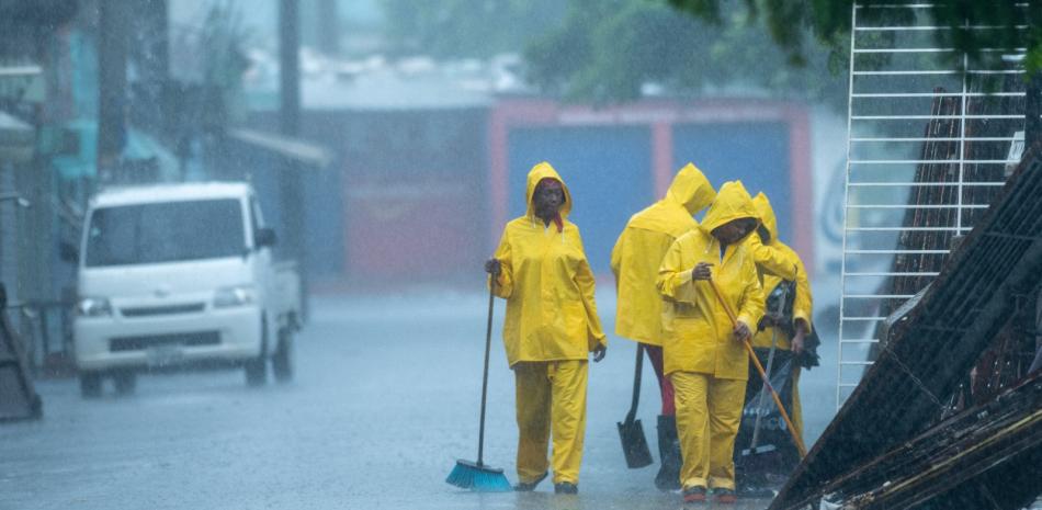 Personal de limpieza trabaja bajo la lluvia.