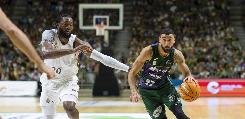 El alero dominicano de Unicaja, Chris Duarte (d), con el balón ante la defensa del pivot angoleño del Real Madrid, Bruno Fernando, durante el tercer partido del XIV Torneo Costa del Sol que han disputado hoy domingo Unicaja y Real Madrid en el Palacio de los Deportes José María Martín Carpena de Málaga. EFE/Carlos Díaz.