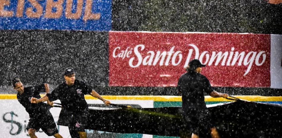 Empleados del Julian Javier colocan la lona en una de las suspensiones que han ocurrido en San Francisco de Macorìs en el joven torneo