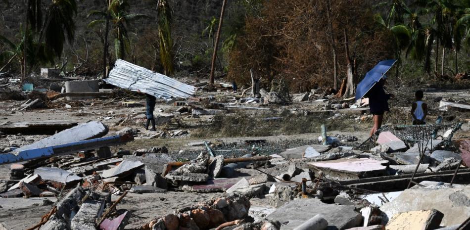 Residentes caminan entre los escombros de una casa dañada tras el paso del huracán Melissa
