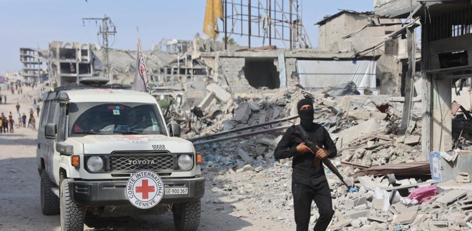 Un militante armado de Hamás se encuentra cerca de un vehículo de la Cruz Roja Internacional (CICR) mientras se lleva a cabo una búsqueda de los cuerpos de rehenes israelíes muertos en la ciudad de Gaza.