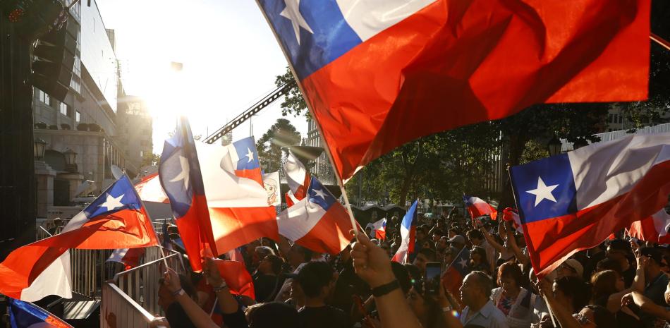 AME9776. SANTIAGO (CHILE), 16/11/2025.- Simpatizantes de la candidata a la Presidencia de Chile por el partido Unidad por Chile, Jeannette Jara, sostienen banderas este domingo, en Santiago (Chile). Los colegios electorales de Chile cerraron sus puertas para arrancar el conteo de votos en unas presidenciales que previsiblemente no se resolverán en primera vuelta y a las que llega como favorita la candidata única del progresismo, Jeannette Jara, pero aparentemente sin el apoyo suficiente para evitar una segunda vuelta. EFE/ Elvis Gonzalez