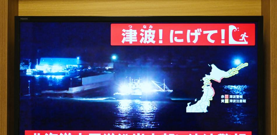 Un aviso que dice "¡Tsunami! ¡Corran!" (arriba) y "Alerta de tsunami emitida para la costa del Pacífico central de Hokkaido" aparece sobre la imagen en directo de un barco saliendo del puerto, en una pantalla de televisión en Sapporo, en la prefectura de Hokkaido, al norte de Japón