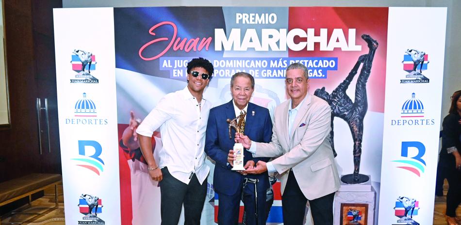 Juan Soto estrella de los Mets  al momento de recibir su premio como ganador del galardón Juan Marichal, quien figura en la foto junto a Mike Pérez, quien es el principal coordinador de este reconocimiento.