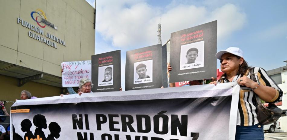 Familiares y miembros de organizaciones de derechos humanos sostienen fotografías y una pancarta con la frase "Ni perdón ni olvido", frente a un tribunal en Guayaquil, Ecuador, durante una audiencia de los militares involucrados en el caso de la desaparición forzada de cuatro menores.