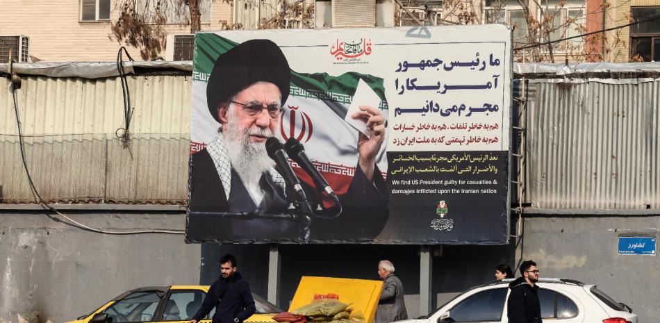 Iraníes pasan junto a una valla publicitaria que muestra al líder supremo iraní, el ayatolá Alí Jamenei, con retórica antiestadounidense en Teherán, el 27 de enero de 2026.