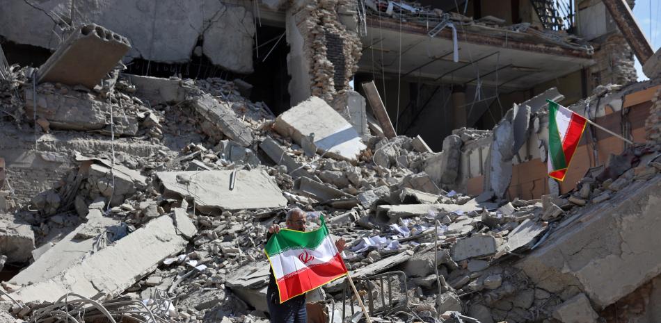 Un hombre sostiene una bandera iraní entre los escombros de un edificio destruido tras los ataques aéreos en el centro de Teherán el 4 de marzo de 2026.