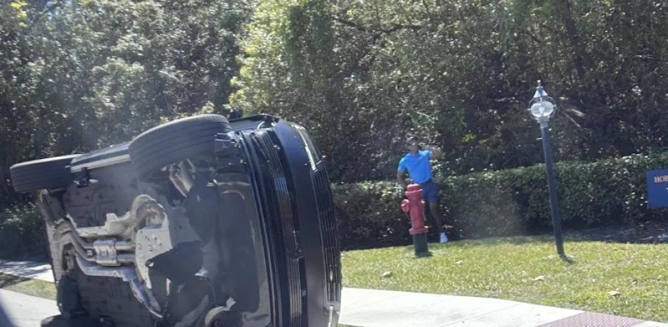 Tiger Woods se encuentra parado a un costado de su vehículo volcado en Jupiter Island, Florida, el viernes 27 de marzo de 2026.