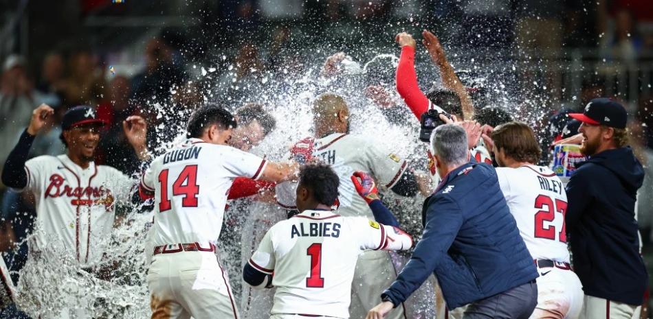 Los Atlanta Braves celebran en el plato tras un grand slam de victoria de Dominic Smith, el centro, en la novena entrada de un partido de béisbol contra los Kansas City Royals.