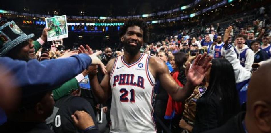 Joel Embiid saluda a varios fanàticos de los Sixers al entrar a la cancha.