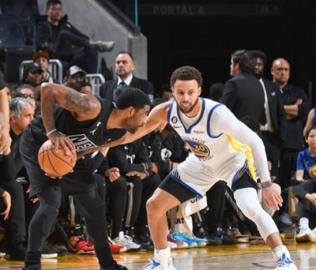 Kyrie Irving, de los Nets, protege el balón ante la defensa de Stephen Curry, de los Warriors, en el partido del domingo por la noche en el baloncesto de la NBA.