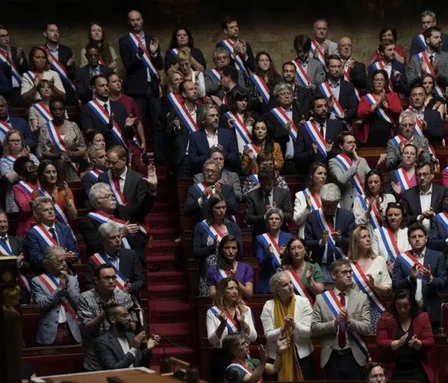 Miembros de la Asamblea Nacional de Francia se ponen en pie y aplauden en homenaje a niños víctimas de un ataque en una localidad de los Alpes franceses, ayer.