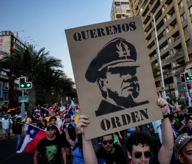 Un hombre sostiene un cartel del fallecido general Augusto Pinochet con el mensaje en español: “Queremos orden”, durante una protesta en Santiago, el 6 de abril de 2023.