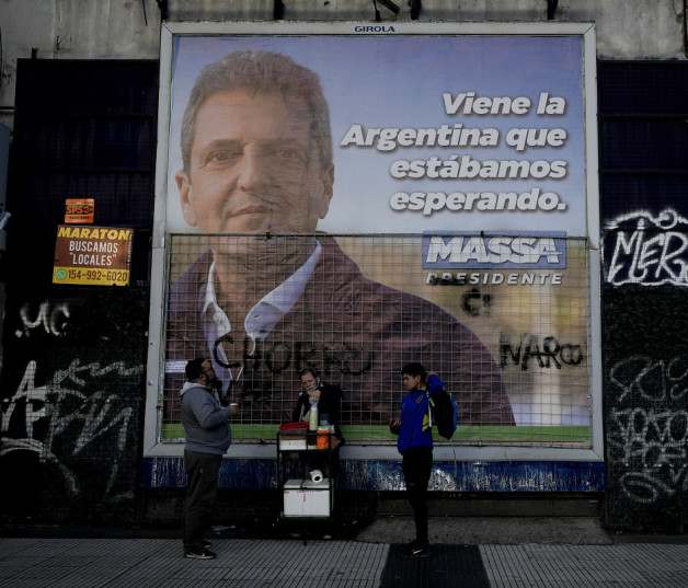 La gente compra café frente a un cartel de campaña del ministro de Economía y aspirante presidencial Sergio Massa en Buenos Aires, Argentina, ayer.
