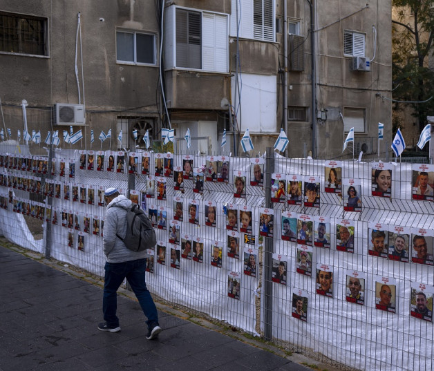 Un hombre pasa junto a una cerca con fotografías de los rehenes, en su mayoría civiles, que fueron capturados por insurgentes de Hamás durante su incursión en el sur de Israel el pasado 7 de octubre, en Ramat Gan, Israel.