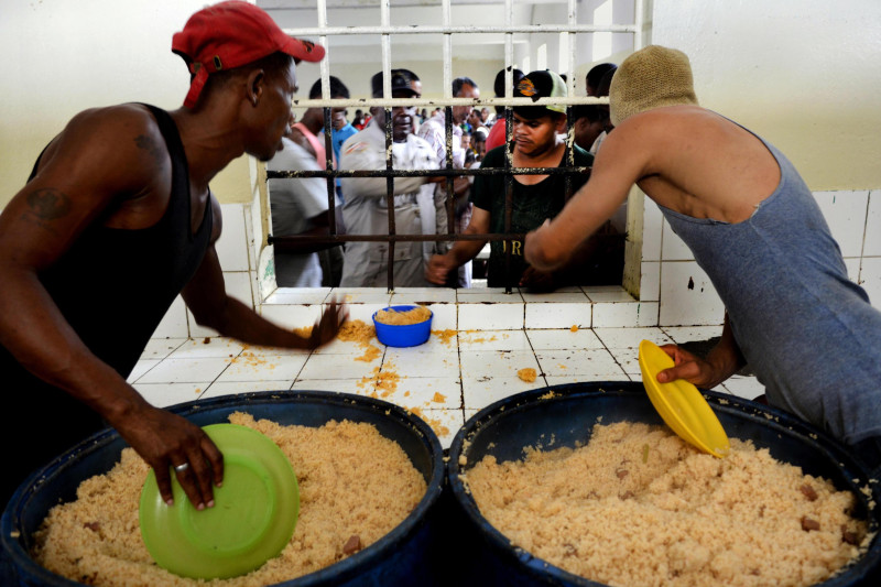 Dos Internos sirven el almuerzo a uno de sus compañeros de la cárcel La Victoria en la República Dominicana.