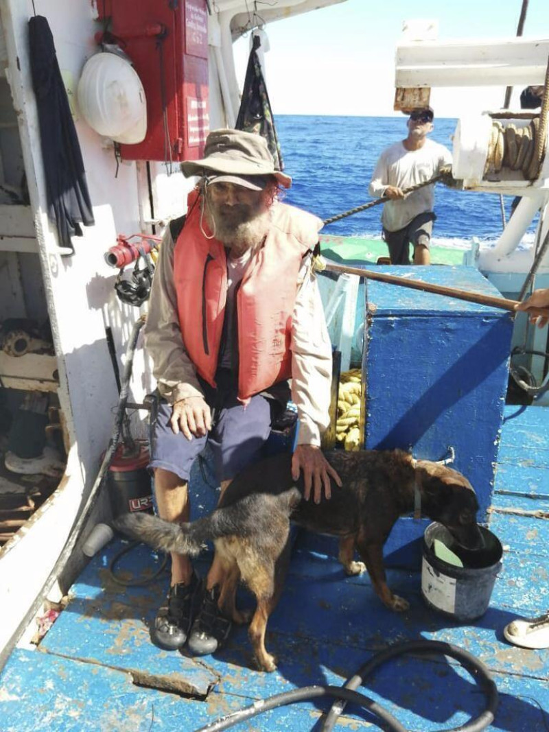 En esta fotografía proporcionada por Grupomar/Atun Tuny, el australiano Tim Shaddock permanece sentado con su perra Bella tras ser rescatado por un buque atunero mexicano en aguas internacionales del Pacífico, luego de que navegó a la deriva con Bella en su catamarán averiado durante tres meses.