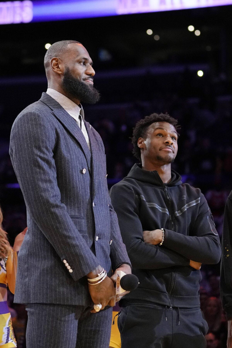 LeBron James (izquierda) y su hijo Bronny escuchan una ceremonia donde se honra al primero como líder anotador en la historia de la NBA, el 9 de febrero de 2023.