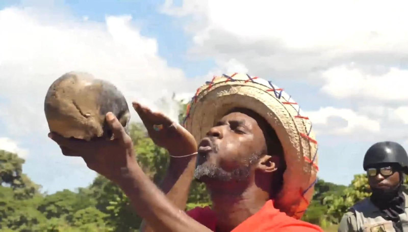 Un brujo haitiano que participó en el ritual ante el río Masacre, sopla ante un cráneo humano buscando el efecto de sus propósitos.