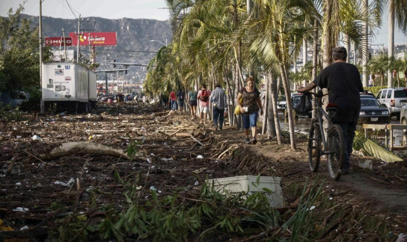 La gente camina junto a los escombros que quedaron después del paso del huracán Otis en Acapulco