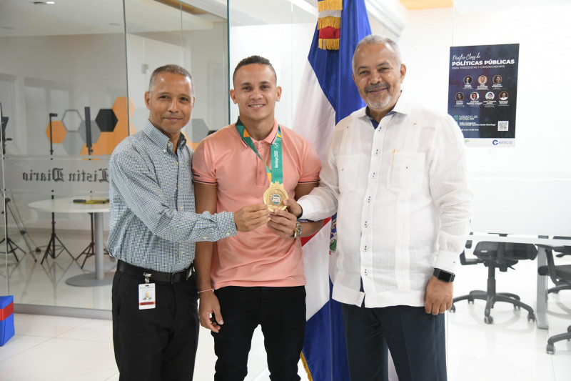 Los subdirectores Juan Salazar y Fabio Abraham sostienen medalla de oro de Audrys Nin Reyes.