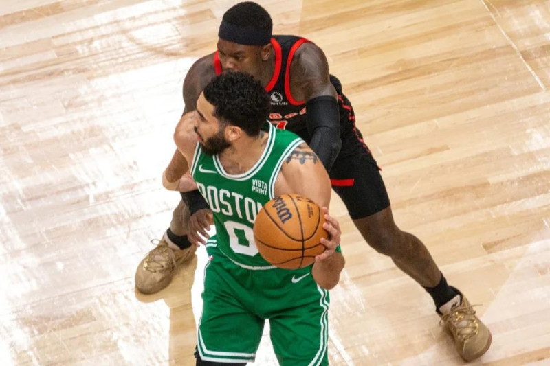 Jason Tatum, de los Celtics, maneja el balón ante la defensa de Dennis Schroeder, de los Raptors, en el partido de la NBA.