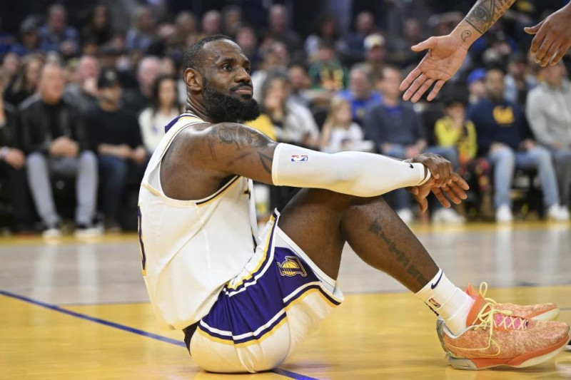 LeBron James, de los Lakers de Los Ángeles, se sienta sobre la cancha tras ser derribado durante el partido ante los Warriors de Golden State.