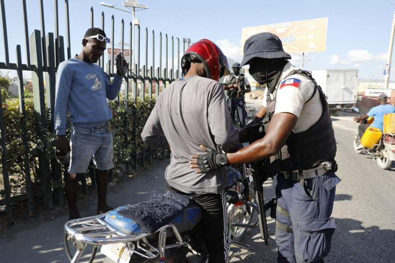 Un policía registra a un motorista en un puesto de control en Puerto Príncipe