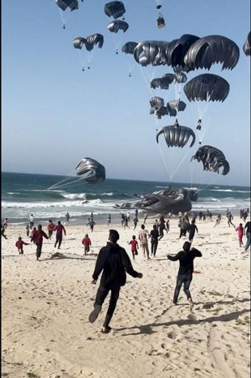 Esta imagen tomada de un vídeo de AFPTV muestra a palestinos corriendo hacia paracaídas sujetos a paquetes de alimentos, lanzados desde aviones estadounidenses en una playa de la Franja de Gaza el 2 de marzo de 2024. El principal aliado de Israel, Estados Unidos, dijo que comenzó a lanzar ayuda desde el aire. Gaza, devastada por la guerra, el 2 de marzo, cuando el Ministerio de Salud del territorio gobernado por Hamás informó de más de una docena de muertes por desnutrición infantil.
