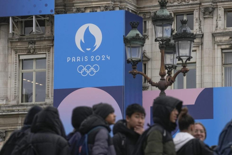 Un grupo de jóvenes frente al Ayuntamiento de París y el logo de los Juegos Olímpicos de París 2024, el martes 5 de marzo de 2024.