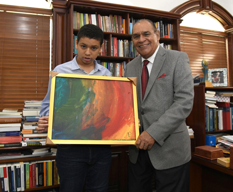 Fotografía muestra al niño autista Fernando Gabriel Quiroz Flaviá, obsequiando una de sus pinturas al director de Listín Diario, Miguel Franjul.