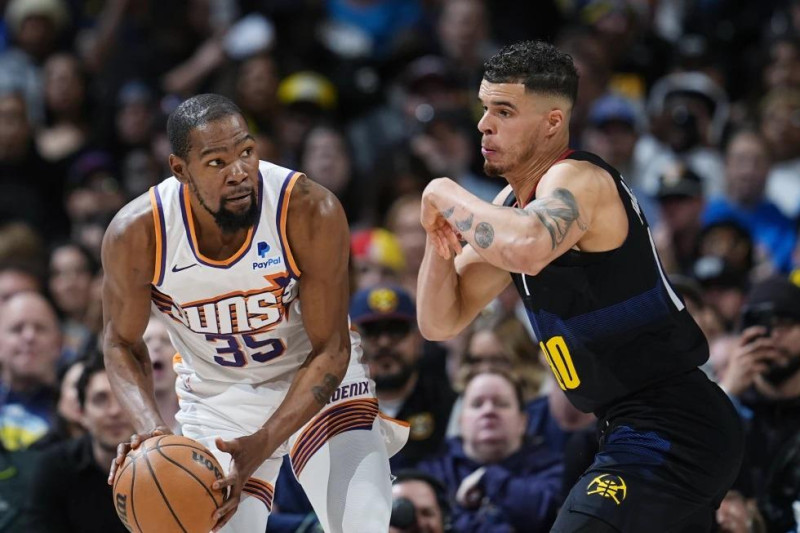 Kevin Durant, alero de los Suns de Phoenix, busca avanzar frente a Michael Porter Jr., de los Nuggets de Denver, en el duelo del miércoles.