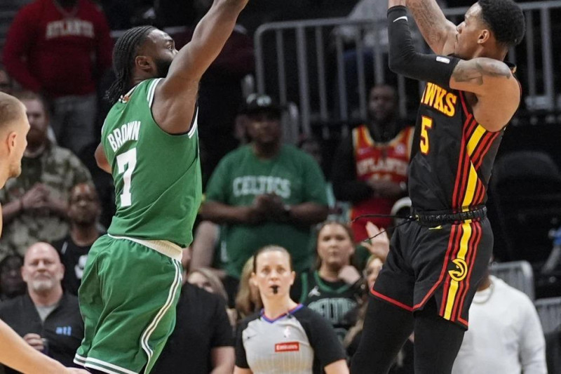 El escolta de los Hawks de Atlanta, Dejounte Murray (5), dispara mientras el escolta de los Celtics de Boston, Jaylen Brown (7), defiende durante el tiempo extra.