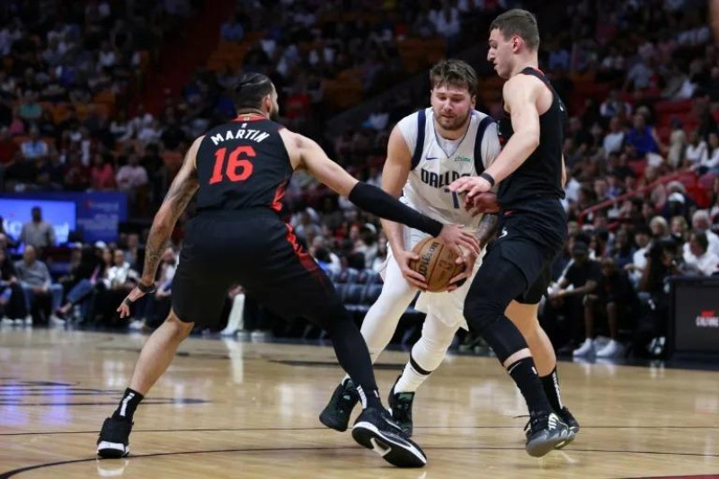 Luka Doncic, de Dallas, maneja el balón ante la defensa de Caleb Martin y Nikola Jovic, de los Heat, en el partido del miércoles en la NBA.