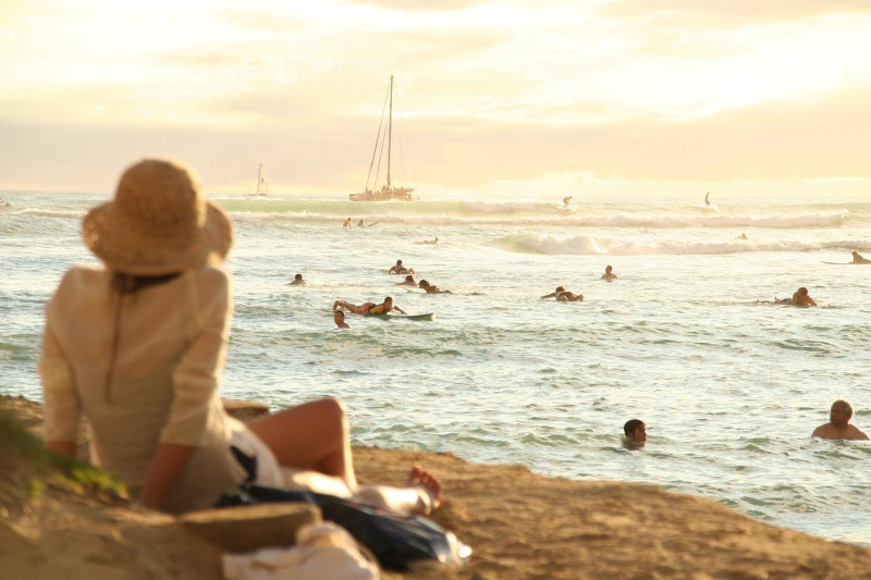 Fotografía muestra mujer disfrutanto del sol y la playa.