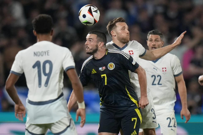 El escocés John McGinn y el suizo Silvan Widmer saltan por el balón durante el encuentro del Grupo A de la Eurocopa en Colonia, Alemania.