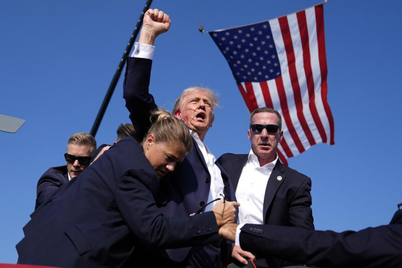 Donald Trump gesticula mientras es escoltado por agentes de seguridad